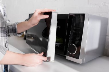 cropped view of woman closing door of microwave in kitchen  clipart