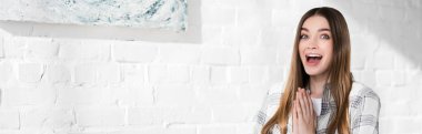panoramic shot of shocked and attractive woman with praying hands 
