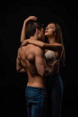 Seksi genç çift, siyah gözleriyle tutkuyla sarılıyorlar.