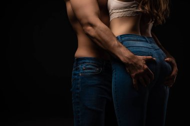Genç ve seksi bir adamın, kız arkadaşının kalçalarına dokunuşunun görüntüsü siyahta izole edilmiş.
