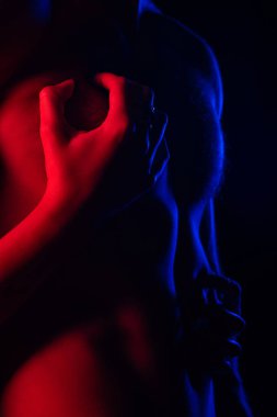 İhtiraslı bir adamın seksi erkek arkadaşına dokunduğu kırmızı ışıkta çıplak bedeninin siyah üzerine izole edildiği görüntüler.