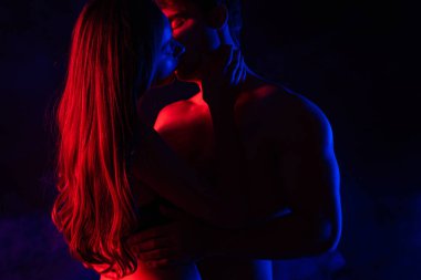 Tutkulu, çıplak, seksi genç çift, kırmızı ışıkta öpüşüyor.