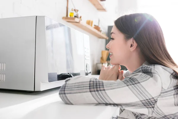 Widok Boku Uśmiechnięta Kobieta Patrząc Kuchenkę Mikrofalową Kuchni — Zdjęcie stockowe