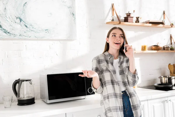 Mulher Sorridente Falando Smartphone Perto Microondas Cozinha — Fotografia de Stock