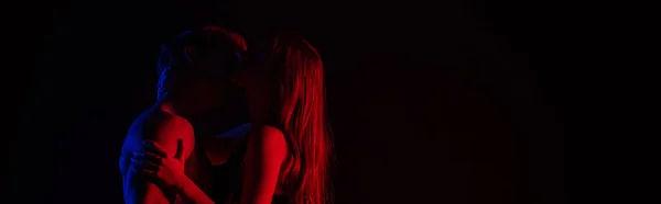 側ビューの服を着ていないセクシーな若いカップルキスと抱擁で赤の光で隔離された黒 パノラマショット — ストック写真