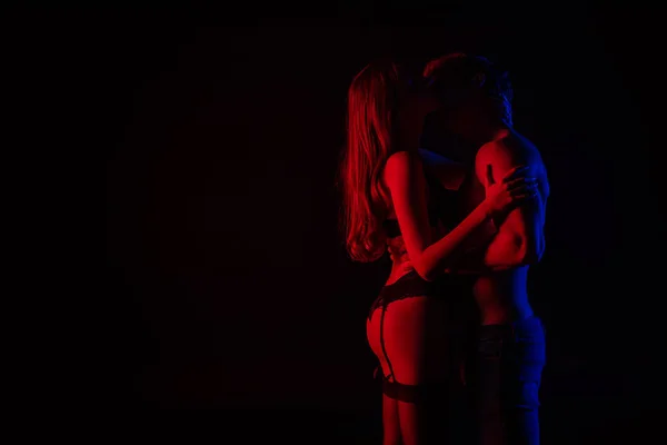 サイドビューのUndressedセクシー若いカップル接吻と抱擁で赤の光隔離された上に黒 — ストック写真