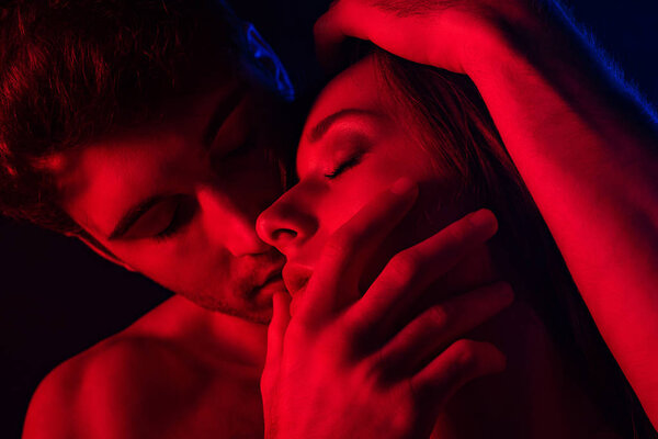 passionate undressed sexy man kissing woman in red light