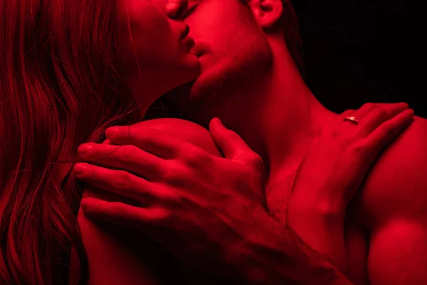 在红光下亲吻的激情四射的年轻夫妇的剪影 与黑色隔离 — 图库照片