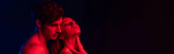 情熱的でセクシーな若いカップル赤の光で隔離された黒 パノラマのショット — ストック写真