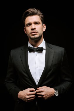 Takım elbiseli şık bir adam siyah cekete dokunuyor. 