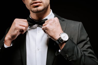 cropped view of man touching bow tie isolated on black  clipart