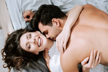 Yatak odasında bir adamın mutlu sevgiliyi öptüğünün en üst görüntüsü 