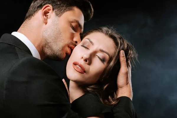Schöner Mann Küsst Junge Frau Mit Geschlossenen Augen Auf Schwarz — Stockfoto