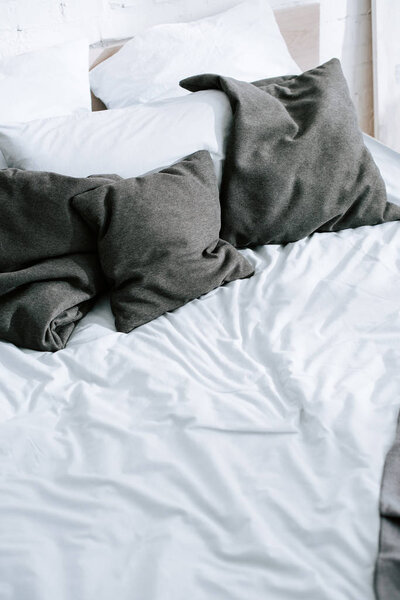 grey pillows on bed with white bedding 