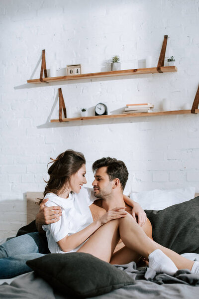 side view of happy shirtless man hugging attractive girlfriend at home 