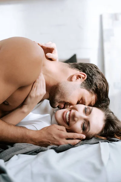 情熱的な男キス幸せなガールフレンドベッドの上に横たわる — ストック写真