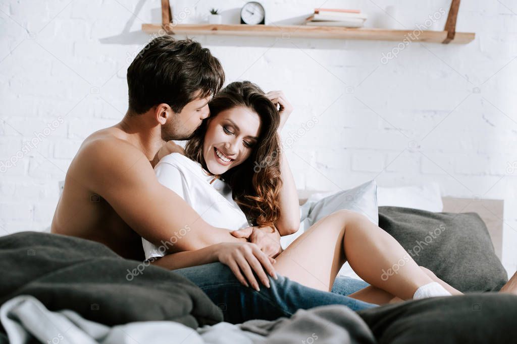 selective focus of man kissing happy girlfriend at home