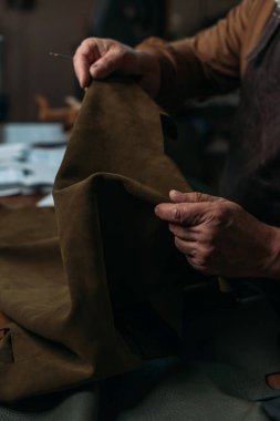 Meyveli turtanın atölyede hakiki deri parçasını tutarken çekilmiş görüntüsü.
