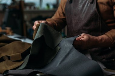 Shoemaker 'ın atölyede elinde hakiki deri parçasıyla kısmi görünümü