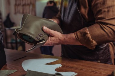 Ayakkabı tamirhanesinde bitmemiş ayakkabının deri detaylarını tutan taraklı bir ayakkabı.