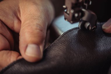 Dikiş makinesine gerçek deri diken ayakkabıcının kırpılmış görüntüsü