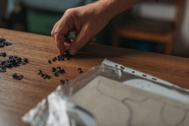 cropped view of shoemaker taking rivets from wooden desk clipart