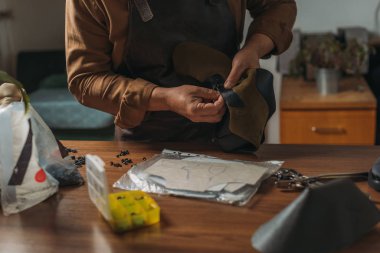 Kırpılmış meyveli turtacı elinde aletlerle masanın yanında deri bir parça tutuyor.