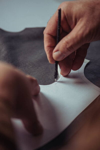 cropped view of shoemaker marking leather with special pen near template