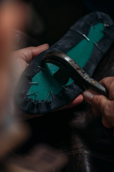 cropped view of cobbler removing nails from boot with nail puller
