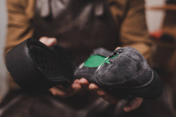 selective focus of shoemaker holding shoe and sole in workshop