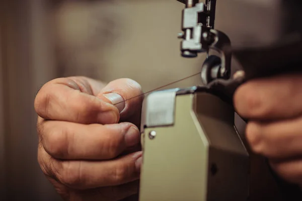 缝纫机上缝制皮革时鞋匠持线的裁剪视图 — 图库照片