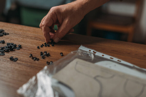 cropped view of shoemaker taking rivets from wooden desk