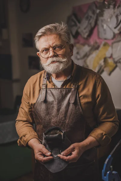 Selbstbewusster Älterer Schuster Blickt Die Kamera Während Lederdetails Der Hand — Stockfoto