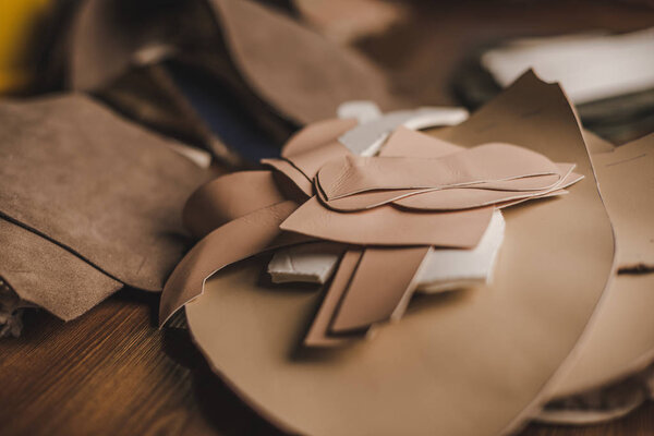 selective focus of leather details on wooden desk in workshop