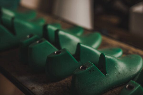 selective focus of different shoe lasts on rack in workshop