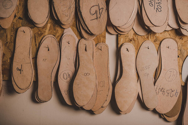 footwear insoles of different sizes hanging on wall in workshop