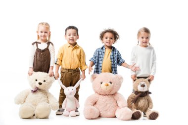 Oyuncak ayılar ve oyuncak ayılarla ayakta duran mutlu çok kültürlü çocuklar.