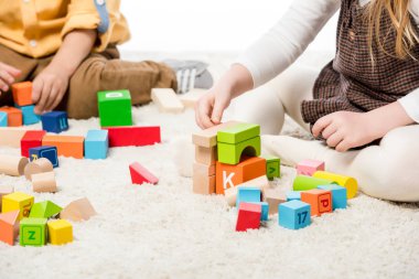 cropped view of children playing with wooden blocks on carpet clipart
