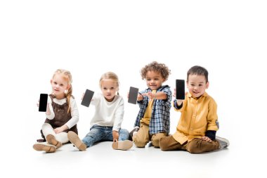 Beyaz ekranlı akıllı telefonları gösteren mutlu çok kültürlü çocuklar.
