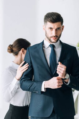 secretary touching hand of confident and handsome businessman in office 
