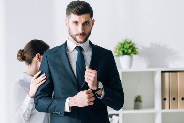 secretary touching hand of confident and handsome businessman in office 