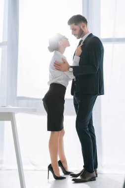 side view of businessman hugging attractive secretary in office 