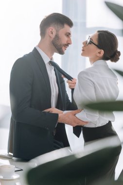 side view of businessman and secretary having love affair in office 