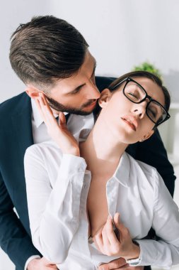businessman kissing attractive secretary with big breast in office 