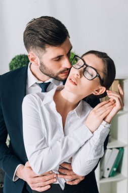 handsome businessman hugging and kissing secretary in office 