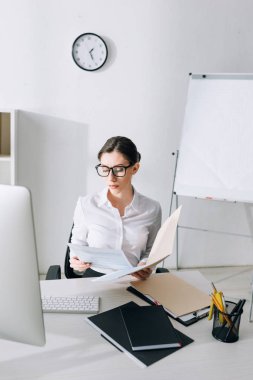 attractive businesswoman sitting at table and doing paperwork 