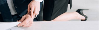 panoramic shot of secretary touching hand of businessman in office 
