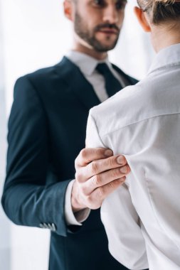 selective focus of businessman touching hand of secretary in office 
