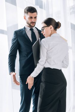 attractive secretary touching leg of shocked businessman in office 