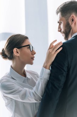 attractive secretary touching shoulder of businessman in office 